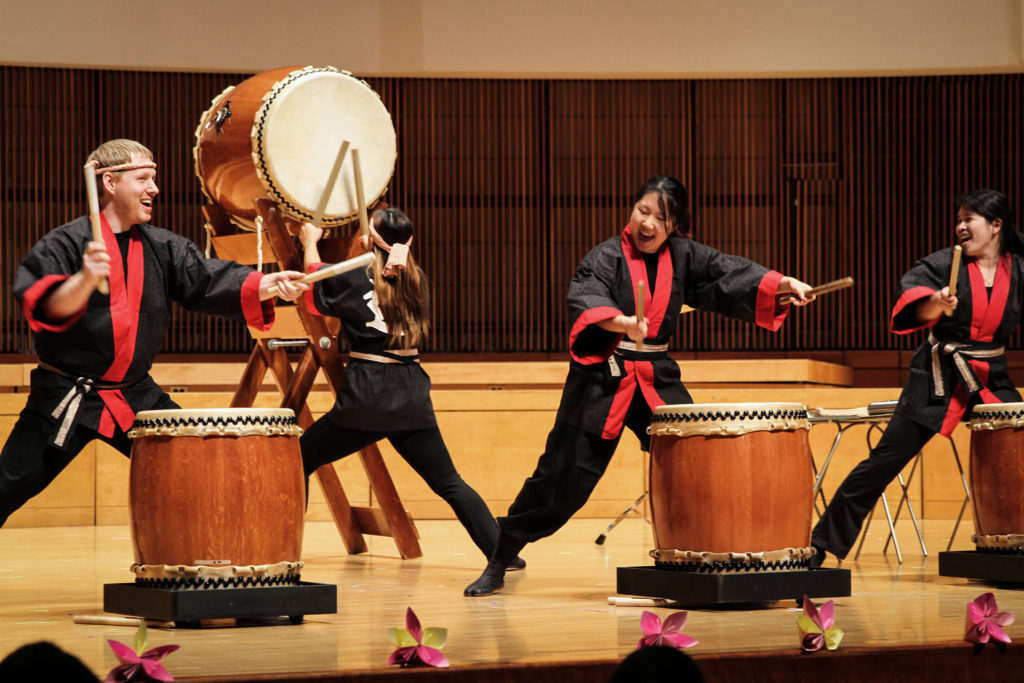 A Japanese taiko drumming ensemble performs on stage